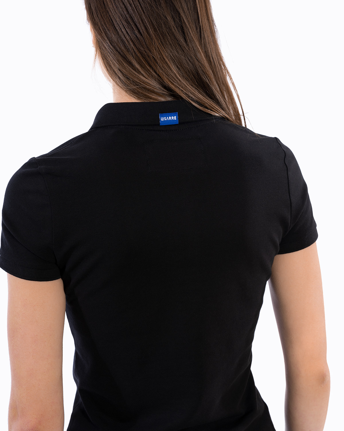 Rückansicht des schwarzen Ladies-Polo-Shirt der Saarland-Marke LA SARRE. Nahaufnahme: Deutlich zu sehen das blaue Saumlabel mit der Aufschrift LA SARRE sowie die Struktur des Piqué-Stoffs. Nicht zu sehen das Sarre-Wappen.