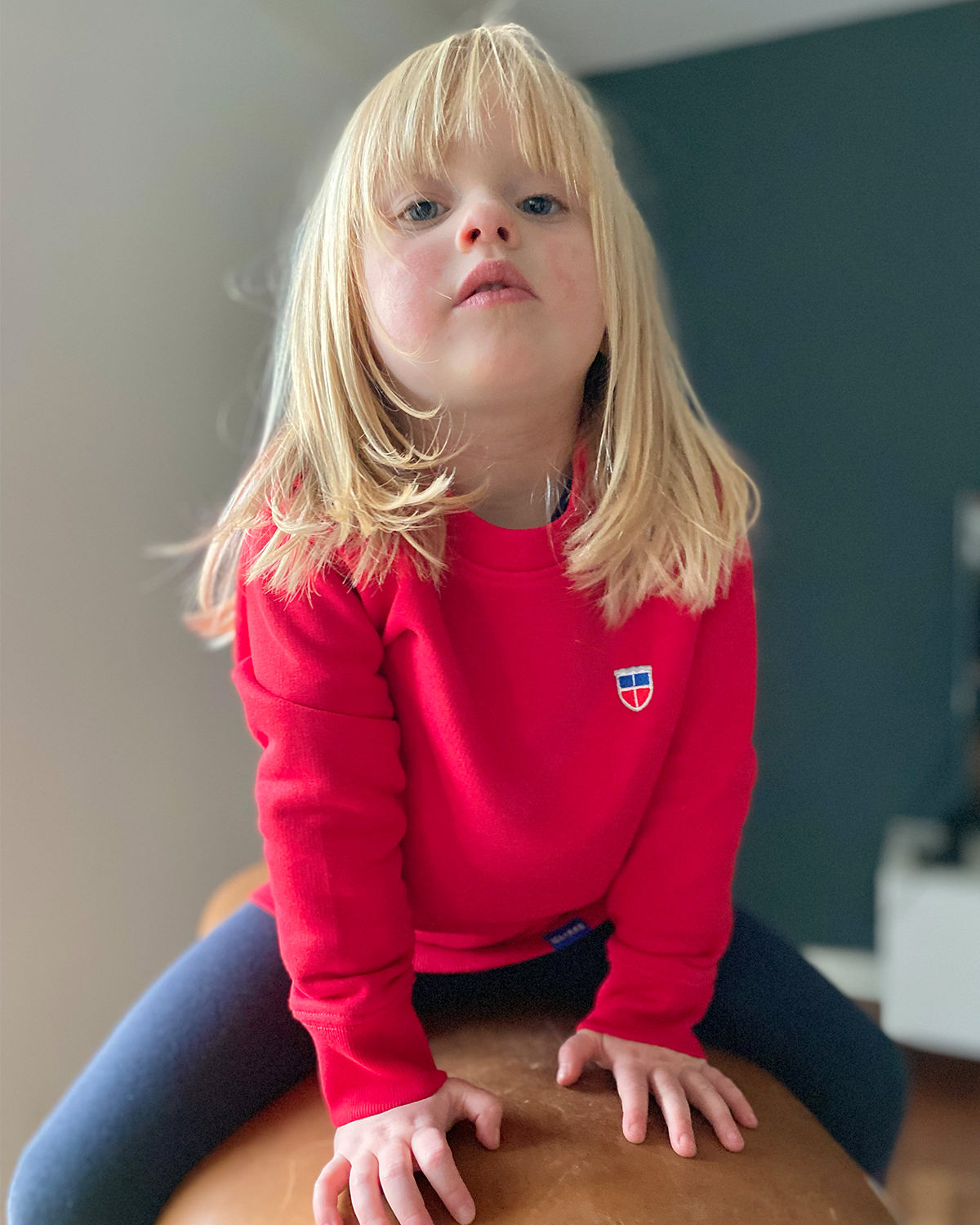 Selma trägt unseren super schönen, knallig-roten Pulli, damit sticht sie überall heraus. Dieses leichte Sweatshirt gibt es für Kinder von 3 bis 14 Jahren.