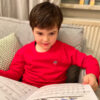 Wir sehen Anton, 5 Jahre alt in unserem Kinder Pullover Tom mit Saarland Wappen auf der linken Brust. Theorie ist aller Anfang: Anton schaut sich ein Notenbuch zum Gitarrenunterricht an.