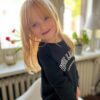 Saarland Geschenk für die Kleinsten: Selma zeigt sich in unserem schicken Kinder-Sweater Modell Leni in klassichem Schwarz mit VIVE LA SARRE College Aufdruck.