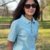Saarland Geschenk T-Shirt. Jessi trägt das gerade geschnittene Unisex-Poloshirt GISÈLE mit Saarwappen in der Farbe Pistache.