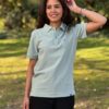Saarland Geschenk T-Shirt. Jessi trägt das gerade geschnittene Unisex-Poloshirt GISÈLE mit Saarwappen in der Farbe Pistache.