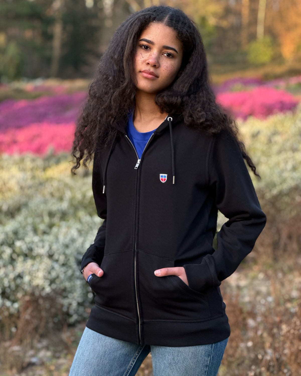 Saarland Geschenk T-Shirt. Jessi trägt den Zipper-Hoodie LARA mit Wappenstick auf der linken Brust in der Farbe Schwarz.